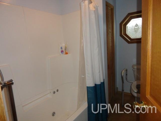 bathroom featuring shower / tub combo with curtain and toilet