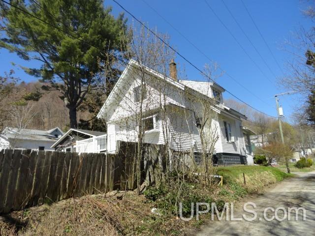 213 Oak St, Munising, MI 49862 - view of side of property featuring fence and a chimney