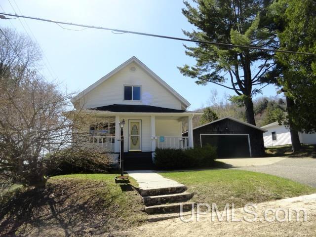 213 Oak St, Munising, MI 49862 - view of front of home with a detached garage and a porch