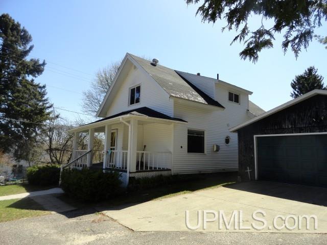 213 Oak St, Munising, MI 49862 - view of front of property featuring a porch, concrete driveway, and an attached garage
