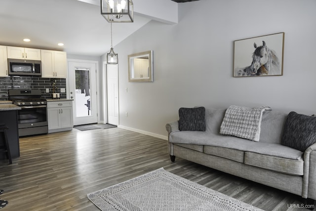 living room featuring dark wood-type flooring, vaulted ceiling, and a notable chandelier