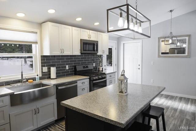 kitchen with sink, hanging light fixtures, stainless steel appliances, a center island, and white cabinets