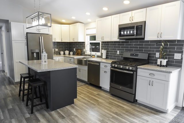 kitchen with sink, a kitchen island, white cabinets, and appliances with stainless steel finishes