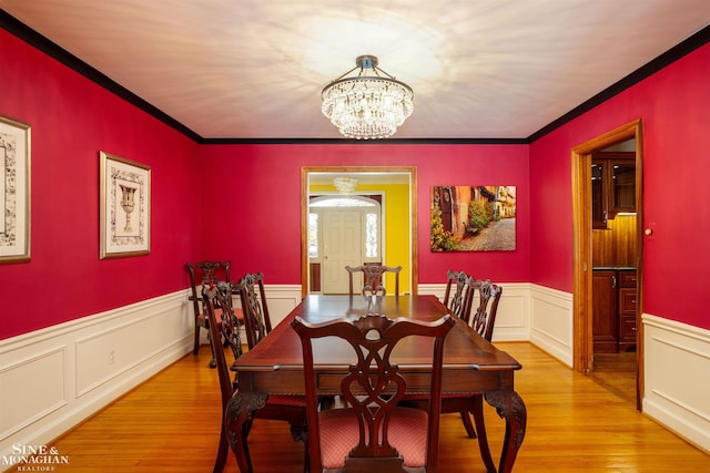 dining area with ornamental molding, a chandelier, and light hardwood / wood-style floors