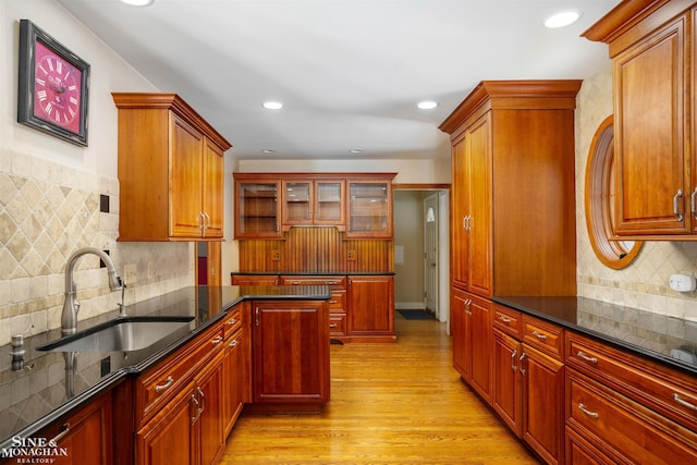 kitchen featuring sink, dark stone countertops, decorative backsplash, and light hardwood / wood-style flooring