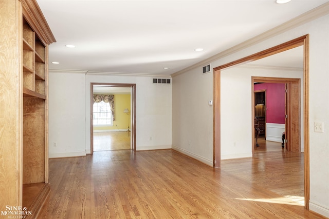 empty room with ornamental molding and light hardwood / wood-style floors