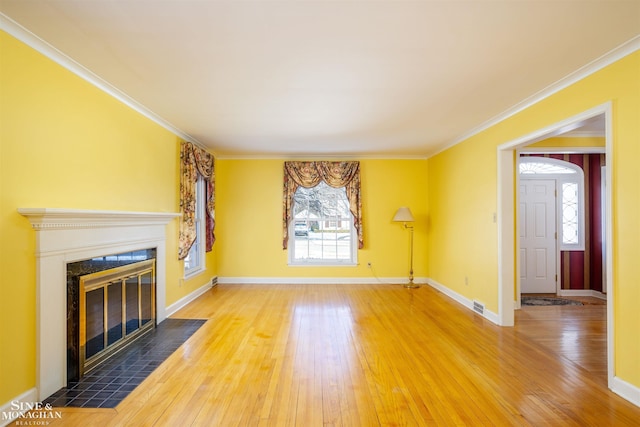 unfurnished living room featuring hardwood / wood-style flooring, a tile fireplace, and ornamental molding