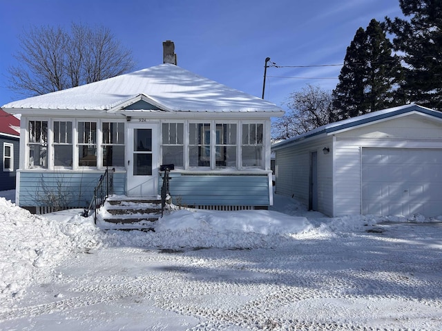 view of front of home with an outbuilding, a garage, and a sunroom