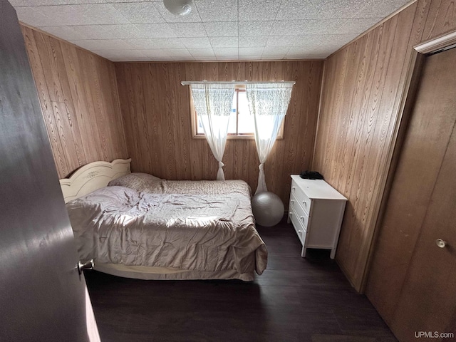 bedroom featuring wooden walls and dark hardwood / wood-style floors