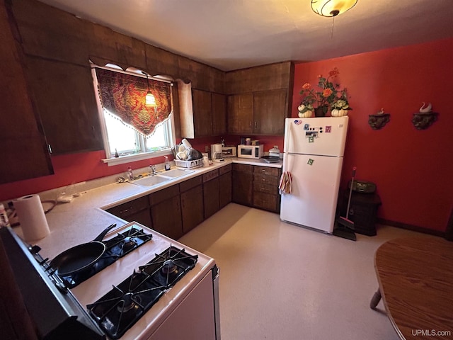 kitchen featuring dark brown cabinetry, sink, white appliances, and decorative light fixtures