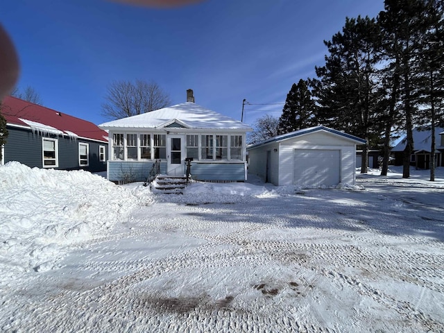 view of front of home featuring a garage, a sunroom, and an outdoor structure