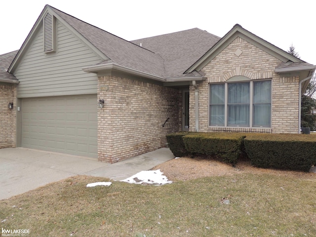 single story home featuring brick siding, roof with shingles, concrete driveway, a garage, and a front lawn