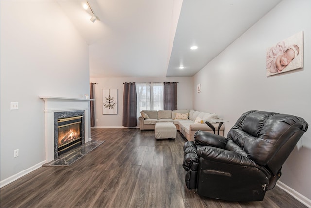 living room featuring lofted ceiling, a high end fireplace, dark hardwood / wood-style floors, and track lighting