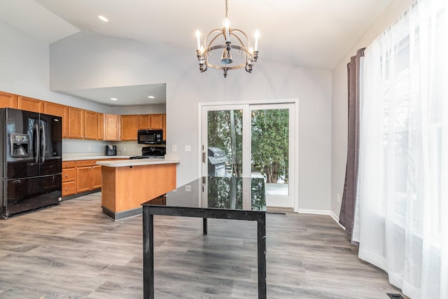 kitchen with decorative light fixtures, kitchen peninsula, light wood-type flooring, and black appliances