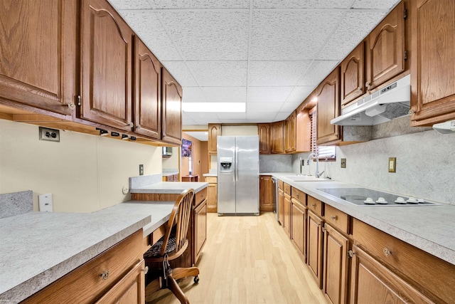 kitchen featuring sink, black electric stovetop, stainless steel refrigerator with ice dispenser, a drop ceiling, and light wood-type flooring