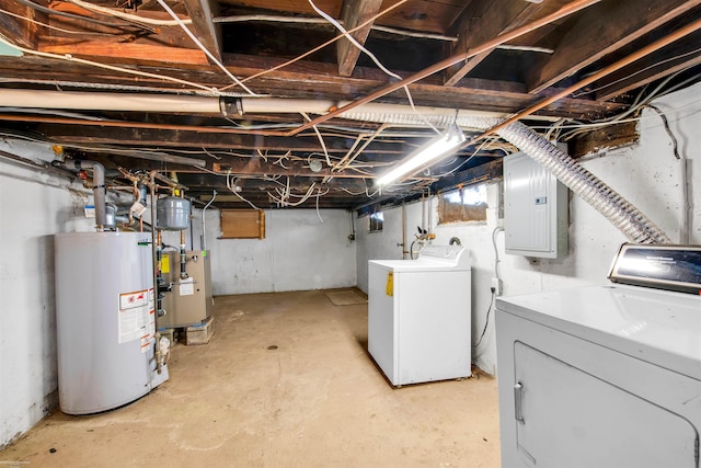 basement featuring washing machine and clothes dryer, electric panel, and gas water heater