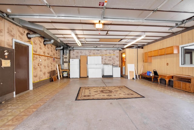 garage featuring washing machine and dryer, wood walls, and white refrigerator