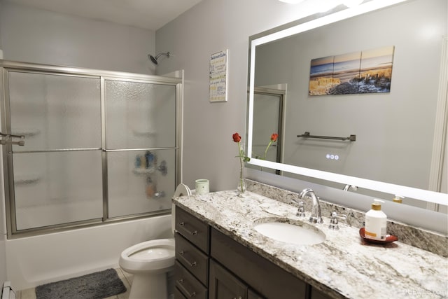 full bathroom featuring bath / shower combo with glass door, a baseboard heating unit, vanity, and toilet