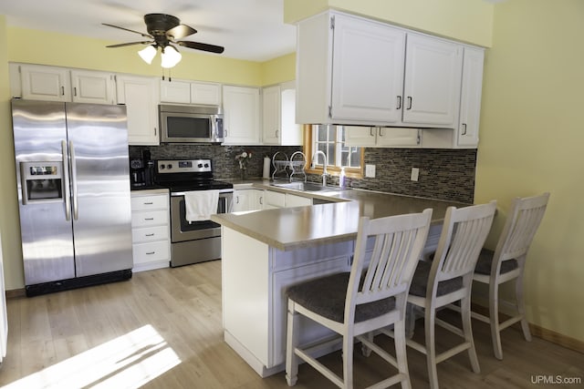 kitchen featuring white cabinetry, sink, backsplash, kitchen peninsula, and stainless steel appliances