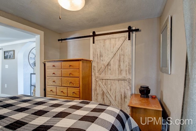 bedroom featuring a barn door and a textured ceiling