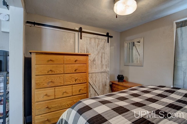 bedroom with a barn door and a textured ceiling