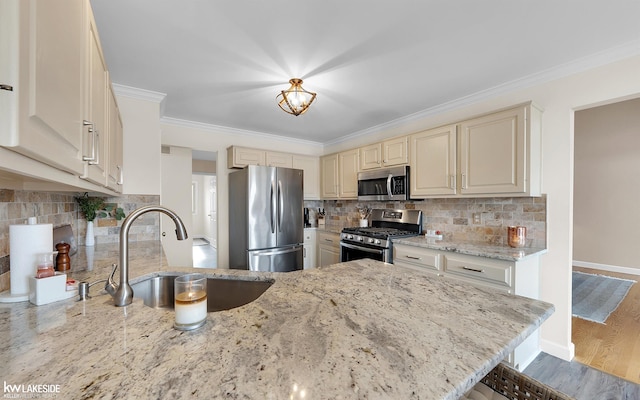 kitchen with stainless steel appliances, sink, light stone counters, and kitchen peninsula