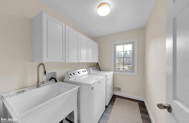 clothes washing area featuring cabinets, sink, washer and dryer, and hardwood / wood-style flooring