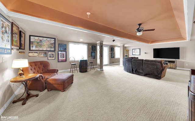 living room with a tray ceiling, carpet floors, ceiling fan, and ornate columns