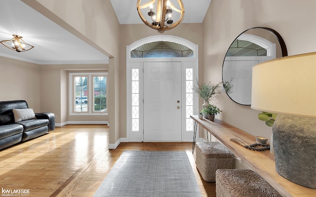 foyer featuring crown molding, light hardwood / wood-style flooring, and a notable chandelier