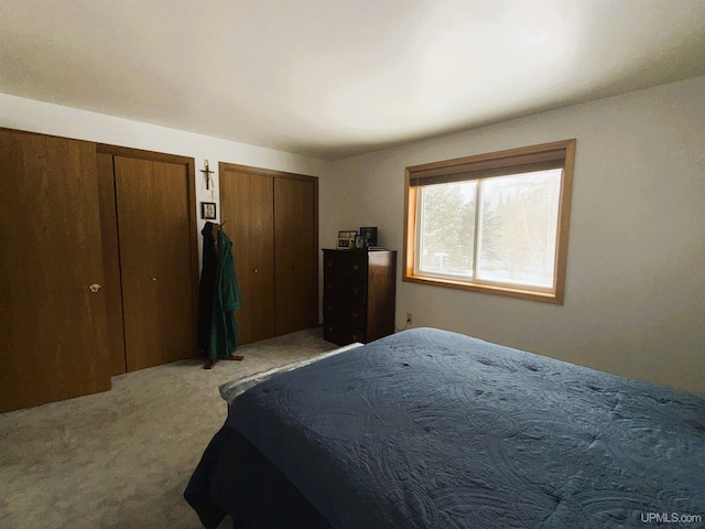 bedroom with multiple closets and light carpet