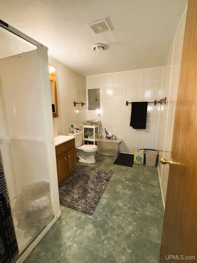 bathroom with vanity, concrete flooring, toilet, and tile walls