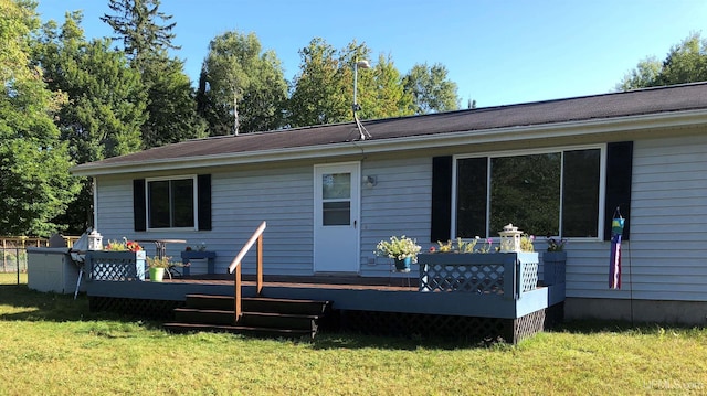 rear view of property featuring a deck and a lawn