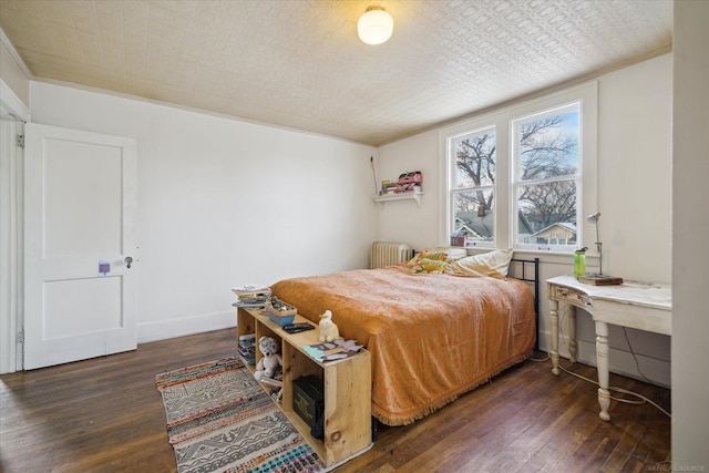 bedroom with dark hardwood / wood-style flooring and radiator