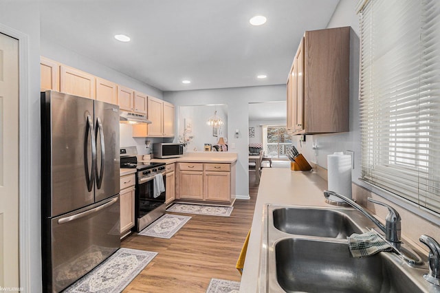 kitchen featuring sink, a notable chandelier, stainless steel appliances, light brown cabinets, and light wood-type flooring