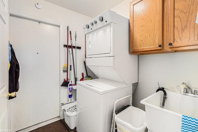 laundry area featuring stacked washer and dryer, cabinets, and sink