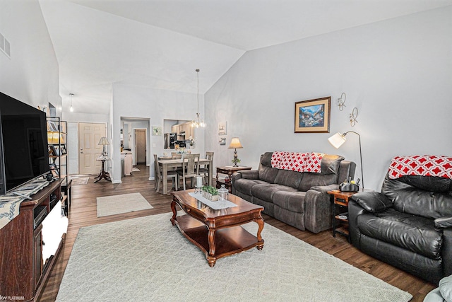 living room with high vaulted ceiling, dark hardwood / wood-style floors, and a chandelier