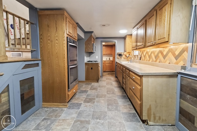 kitchen with stainless steel appliances, ornamental molding, sink, and backsplash