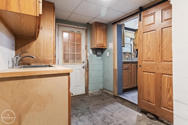 interior space with a drop ceiling, sink, and a barn door