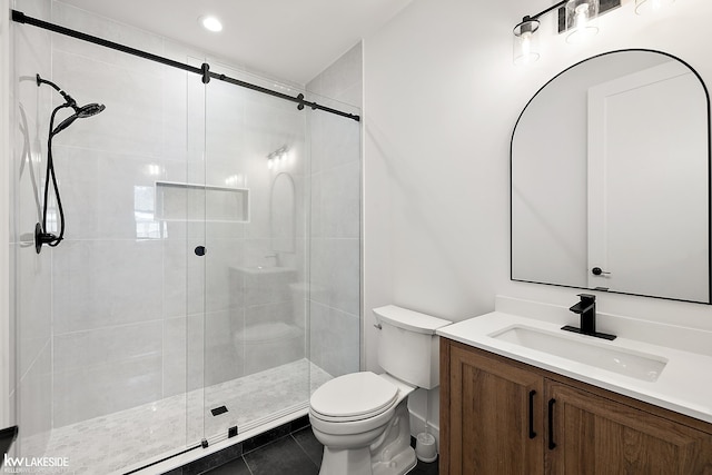 bathroom featuring tile patterned flooring, vanity, a shower with shower door, and toilet