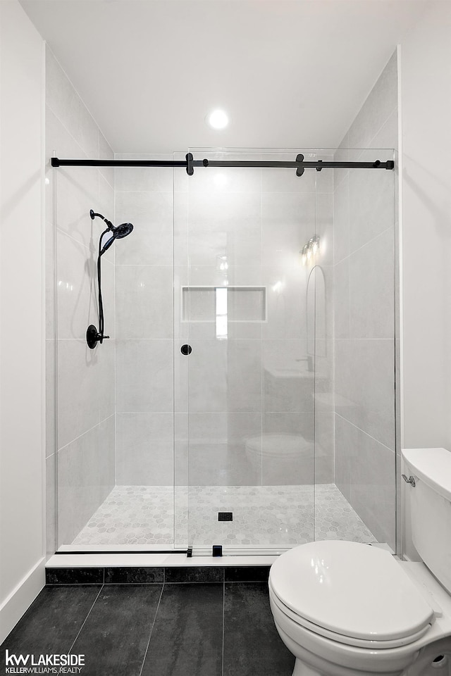 bathroom with toilet and a shower with shower door