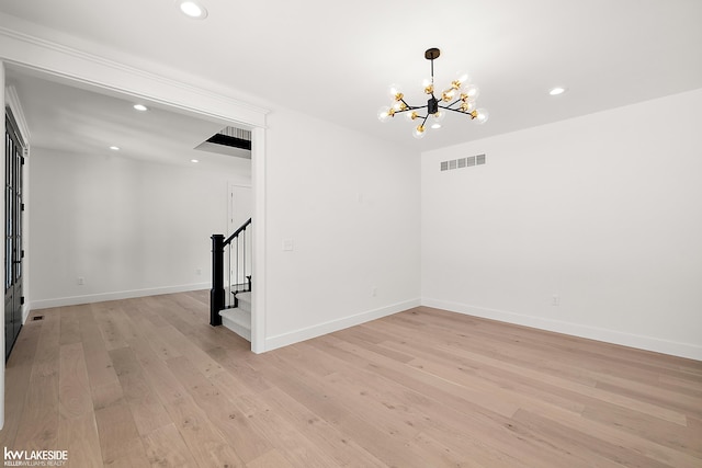 unfurnished room with an inviting chandelier and light wood-type flooring