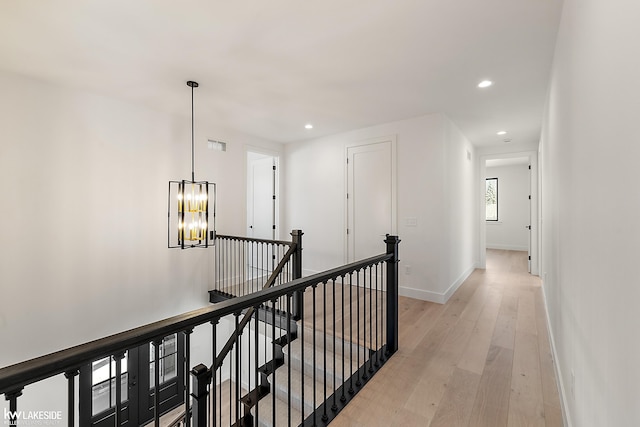 corridor with a notable chandelier and light hardwood / wood-style flooring