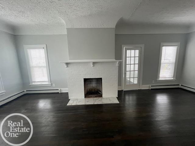 unfurnished living room with dark hardwood / wood-style flooring, a fireplace, a textured ceiling, and baseboard heating