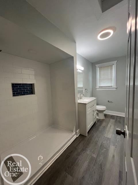 bathroom with wood-type flooring, a shower, vanity, and toilet