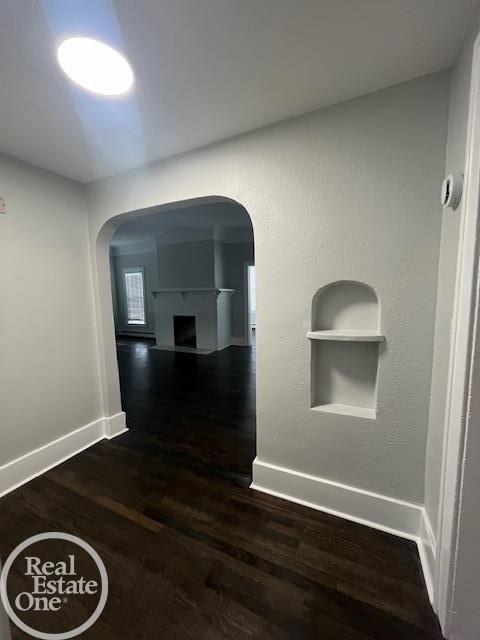 corridor featuring dark wood-type flooring and built in features