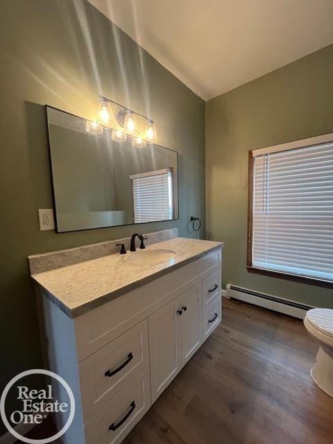 bathroom with vaulted ceiling, wood-type flooring, vanity, baseboard heating, and toilet