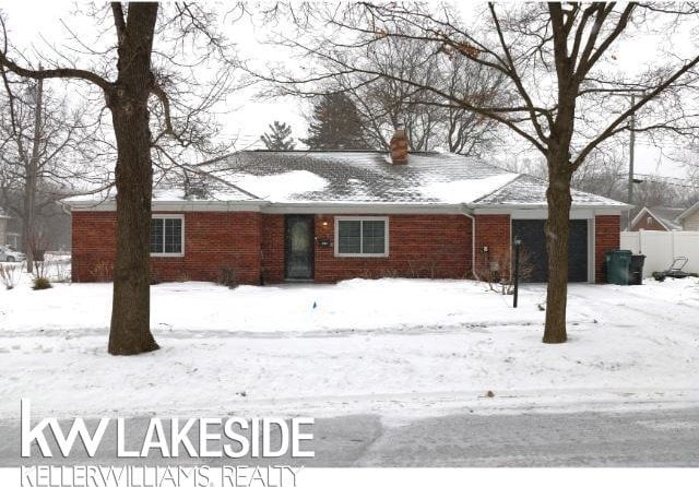 ranch-style house with a garage, brick siding, and fence