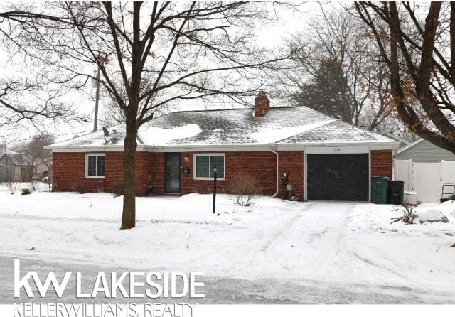 ranch-style house featuring brick siding, a chimney, an attached garage, and fence