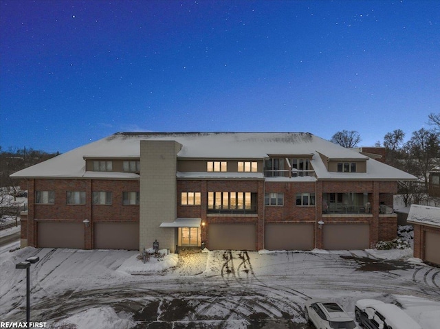 snow covered rear of property featuring a garage