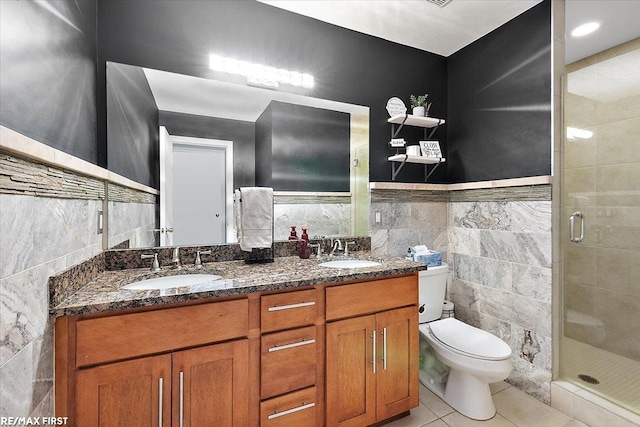 bathroom featuring tile patterned flooring, toilet, tile walls, vanity, and walk in shower